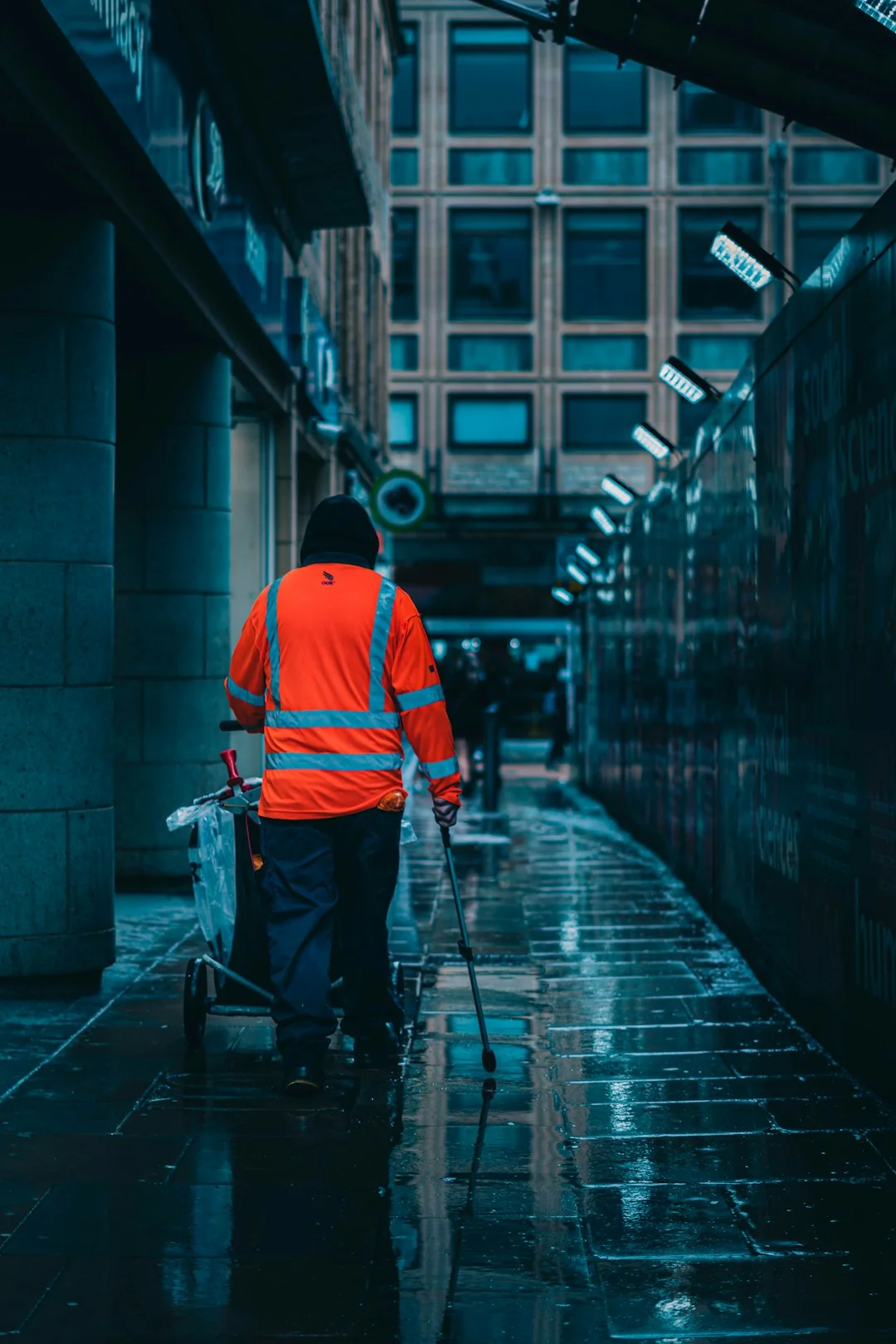 Un homme nettoie les vitres d’un gratte-ciel avec un harnais, illustrant le travail en hauteur en milieu urbain.